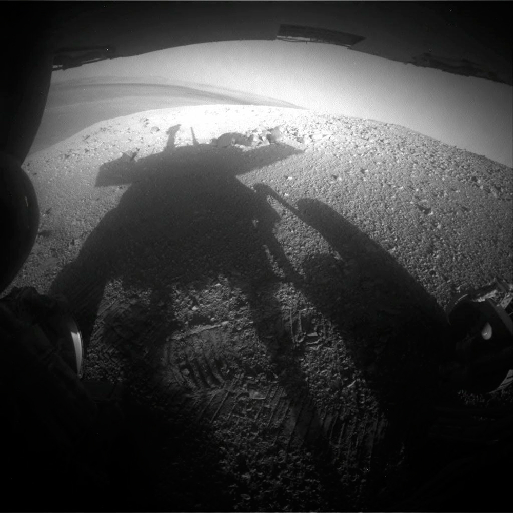 NASA's Mars Exploration Rover Opportunity's rear hazard avoidance camera captures its own shadow on March 20, 2014. The rover's shadow falls across a slope called the McClure-Beverlin Escarpment on the western rim of Endeavour Crater, where Opportunity is investigating rock layers for evidence about ancient environments on Mars.