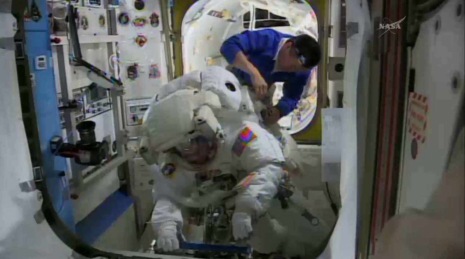 This April 23, 2014 NASA TV image shows International Space Station(ISS) astronauts Koichi Wakata of Japan as he helps Rick Mastracchio of the US(front) prepare for a spacewalk to install a backup computer that failed earlier this month.
