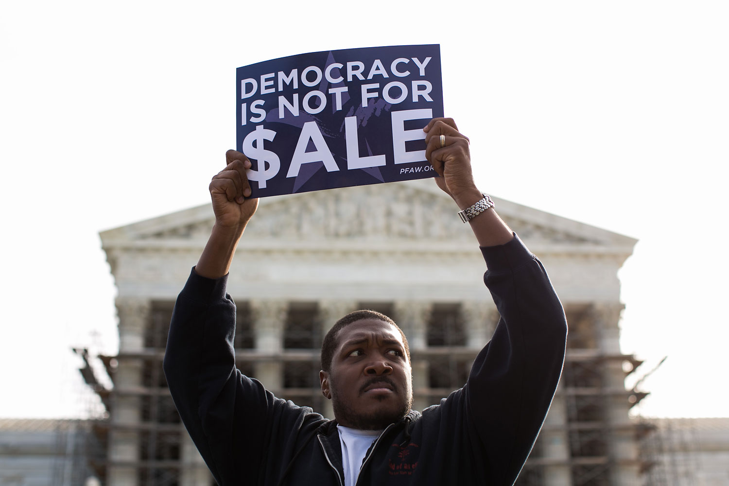Cornell Woolridge holds a sign as he rallies against money in politics, at the Supreme Court in Washington, on October 8, 2013 in Washington, DC.