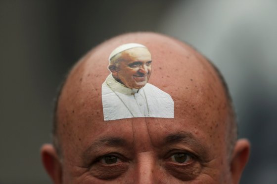 Catholic faithful with sticker bearing an image of Pope Francis on his forehead looks on while waiting for the Pope to arrive in Copacabana beach in Rio de Janeiro