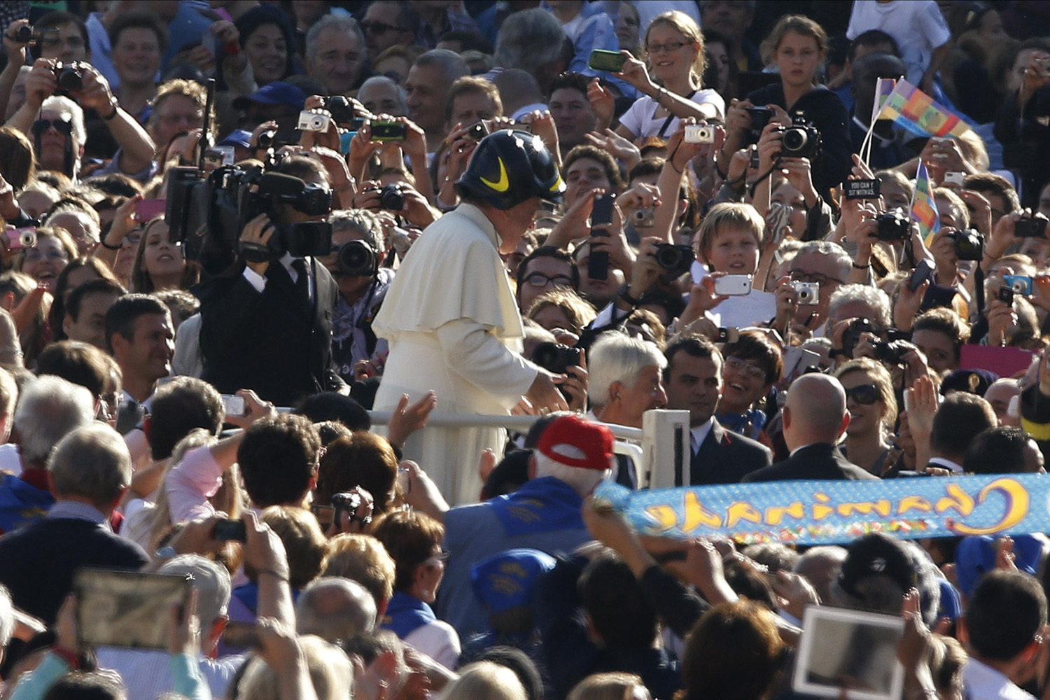 Pope Francis wears a firefighter helmet as he arrives to lead his Wednesday general audience in Saint Peter's square at the Vatican