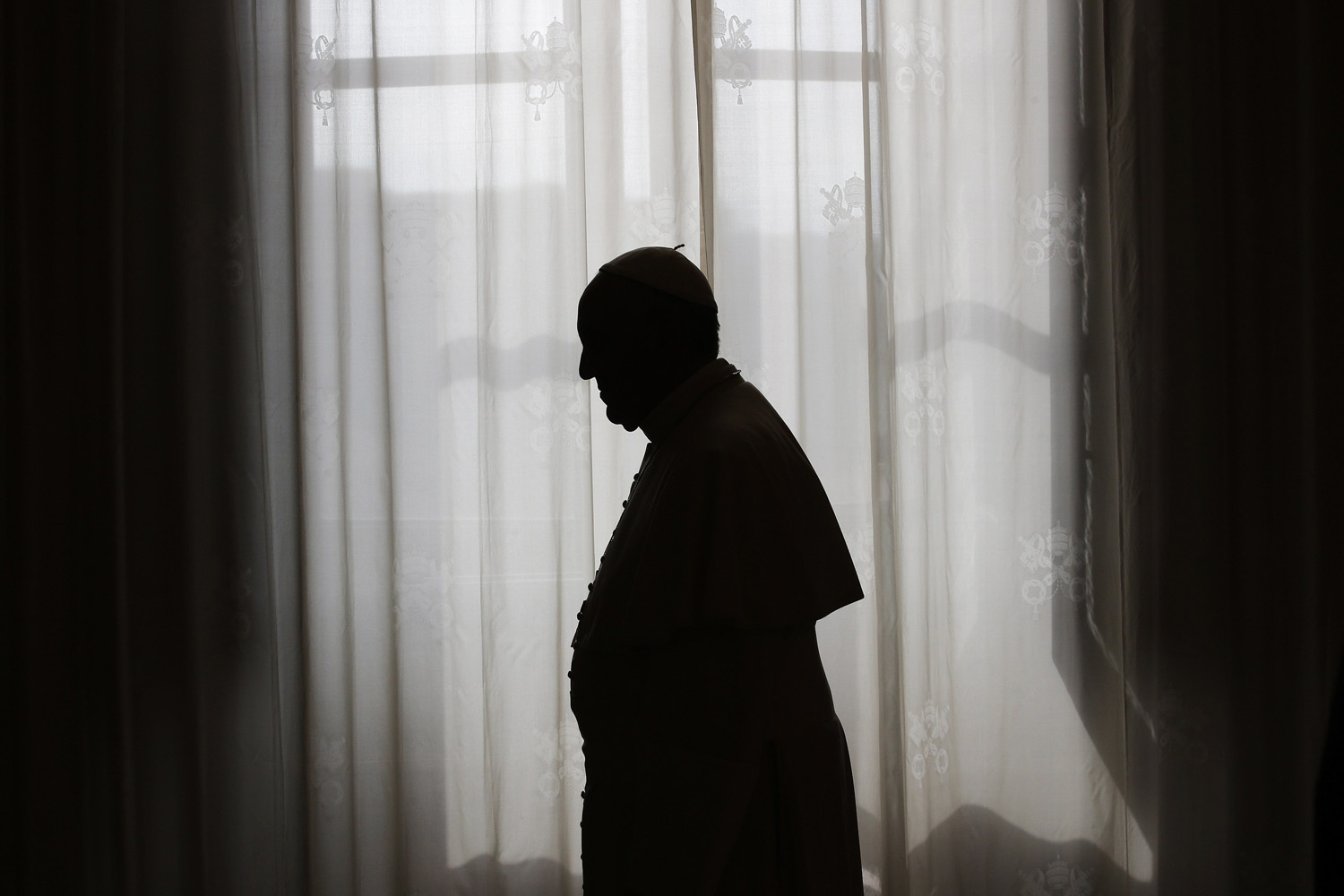 Pope Francis is silhouetted against window light at the end of a meeting at the Vatican