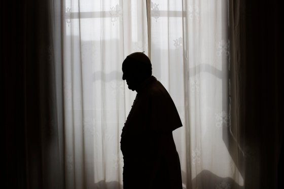 Pope Francis is silhouetted against window light at the end of a meeting at the Vatican