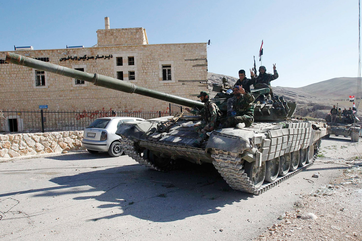 Soldiers loyal to Syria's President Bashar al-Assad gesture from their tank, as they pass Mar Bacchus Sarkis monastery, in Maloula village, northeast of Damascus, after taking control of the village from rebel fighters April 14, 2014. 