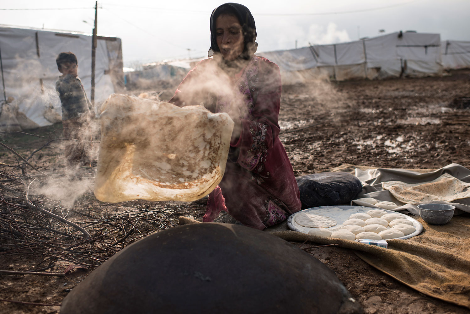 Nafat, 45, from Homs, bakes bread outside her shelter in Turbide, Bekaa Valley. She has been in Lebanon for more than a year, and feeds her family of 13 every morning. “The bakery is too expensive,” she says. “I learned to bake by watching my neighbours."