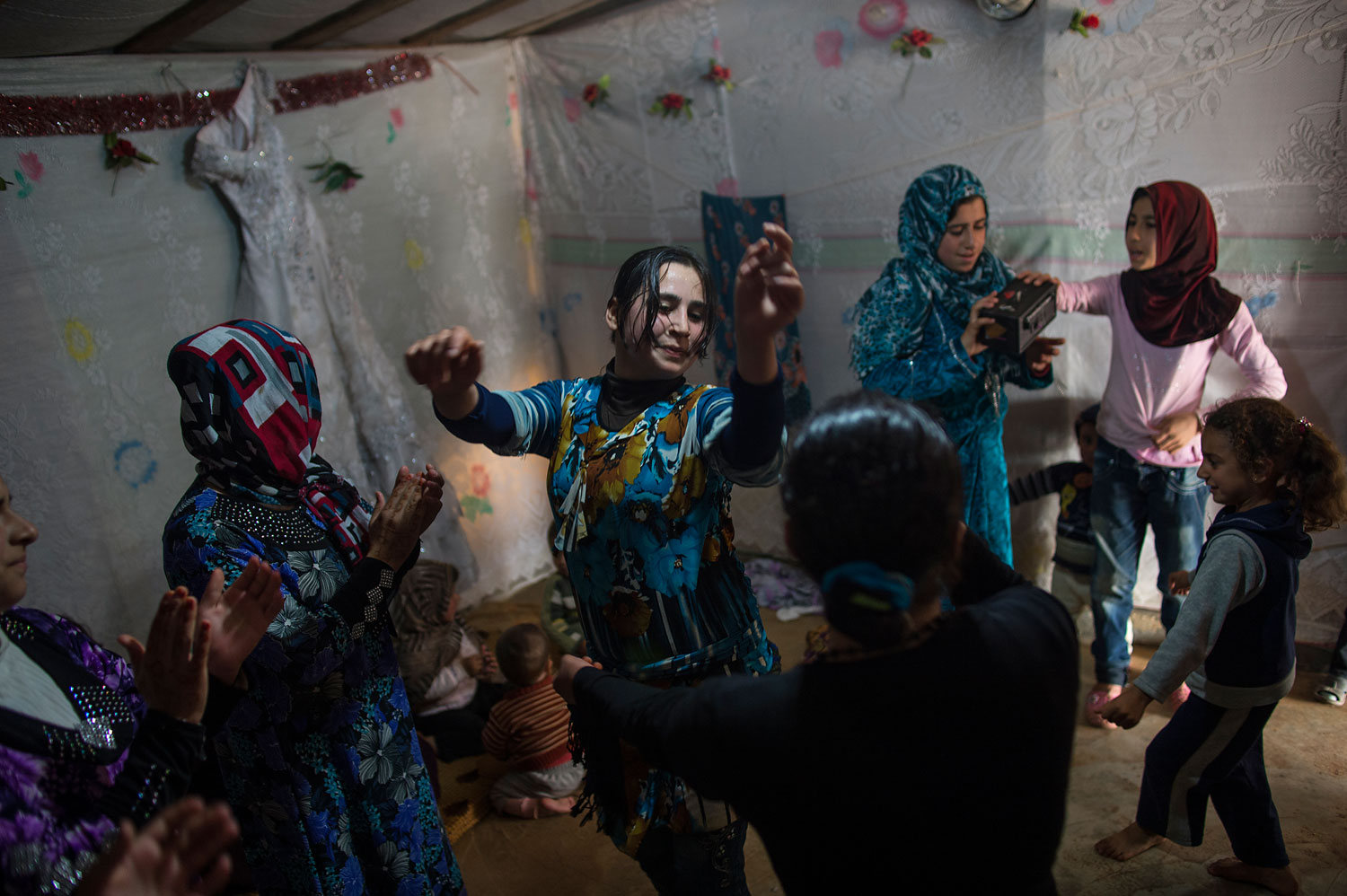 Female Syrian refugees dance around at a wedding celebration in a refugee camp in Marj El-Khokh, in Marjaayoun, Syrian, March 6, 2014. The bride, Yousra, 16, (not shown) was marrying Ahmed, 21, from East Ghouta, Syria. The father of the groom spoke about the wedding "we want to create life out of death and from sadness we want to create happiness. People should not continue to be morbid."