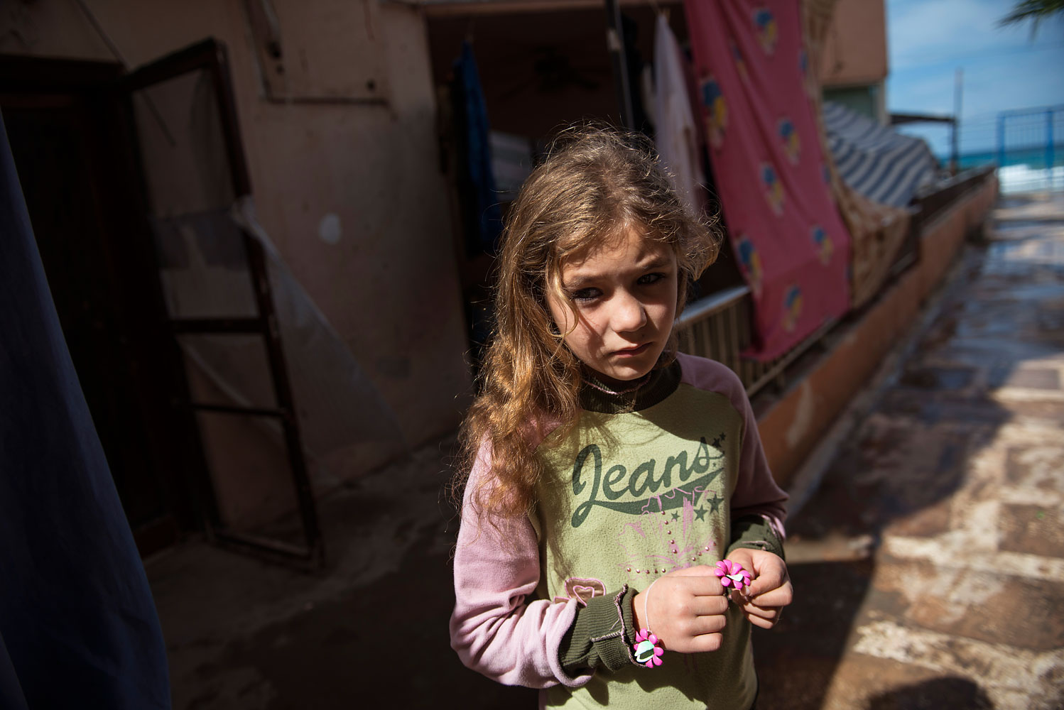 Syrian refugee Ranya, 10, from the Idlib countryside, stands outside her family's room in the Nour resort, a collective shelter that houses roughly 500 Syrian refugees in Tripoli, in Herri, in North Lebanon, March 10, 2014. Ranya and her family fled Idlib about one year ago after the bombing intensified; she has been out of school for three years.