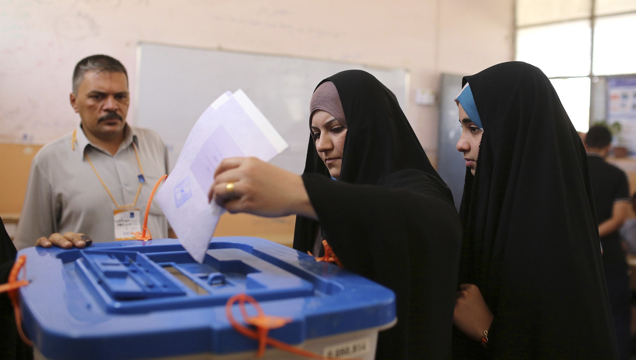A resident casts her ballot at a polling station during Iraqi parliamentary election in Najaf