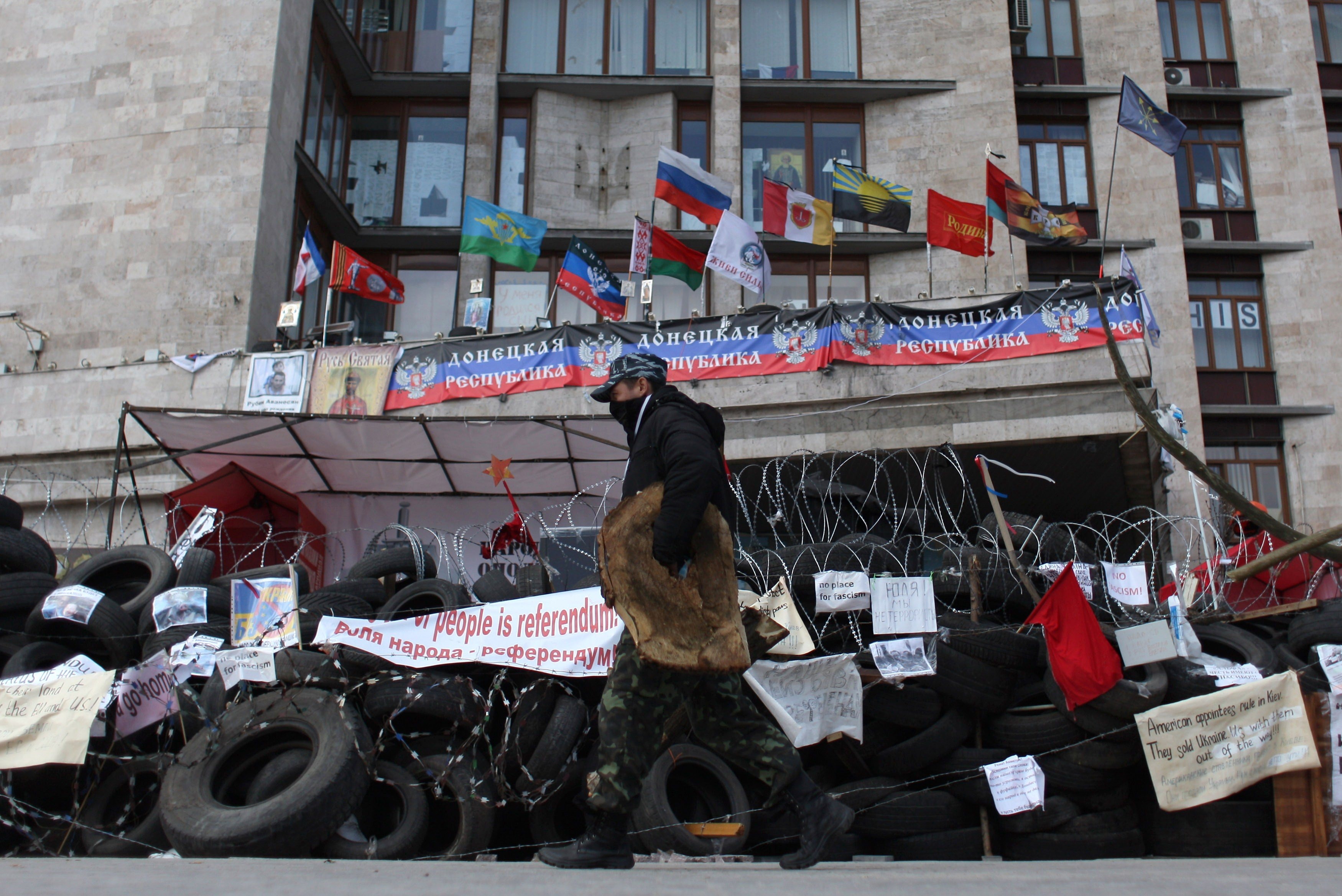 A pro-Russian activist walks in front a barricade set up outside the regional administrative building in the eastern Ukrainian city of Donetsk on April 21, 2014. 