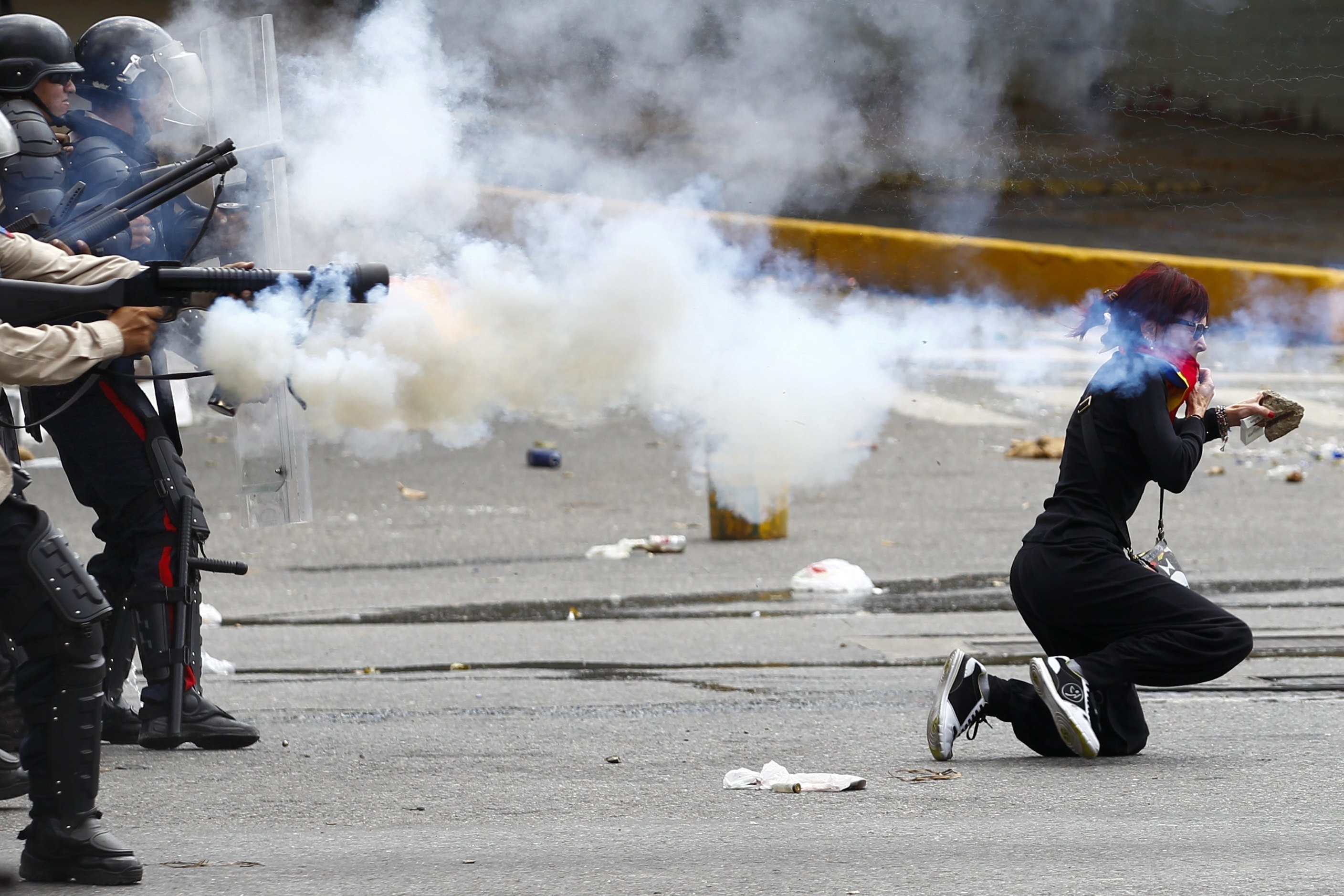 <strong>Growing unrest</strong> An antigovernment protester ducks for cover as Venezuelan police fire tear gas during riots in Caracas (Carlos Garcia Rawlins—Reuters)