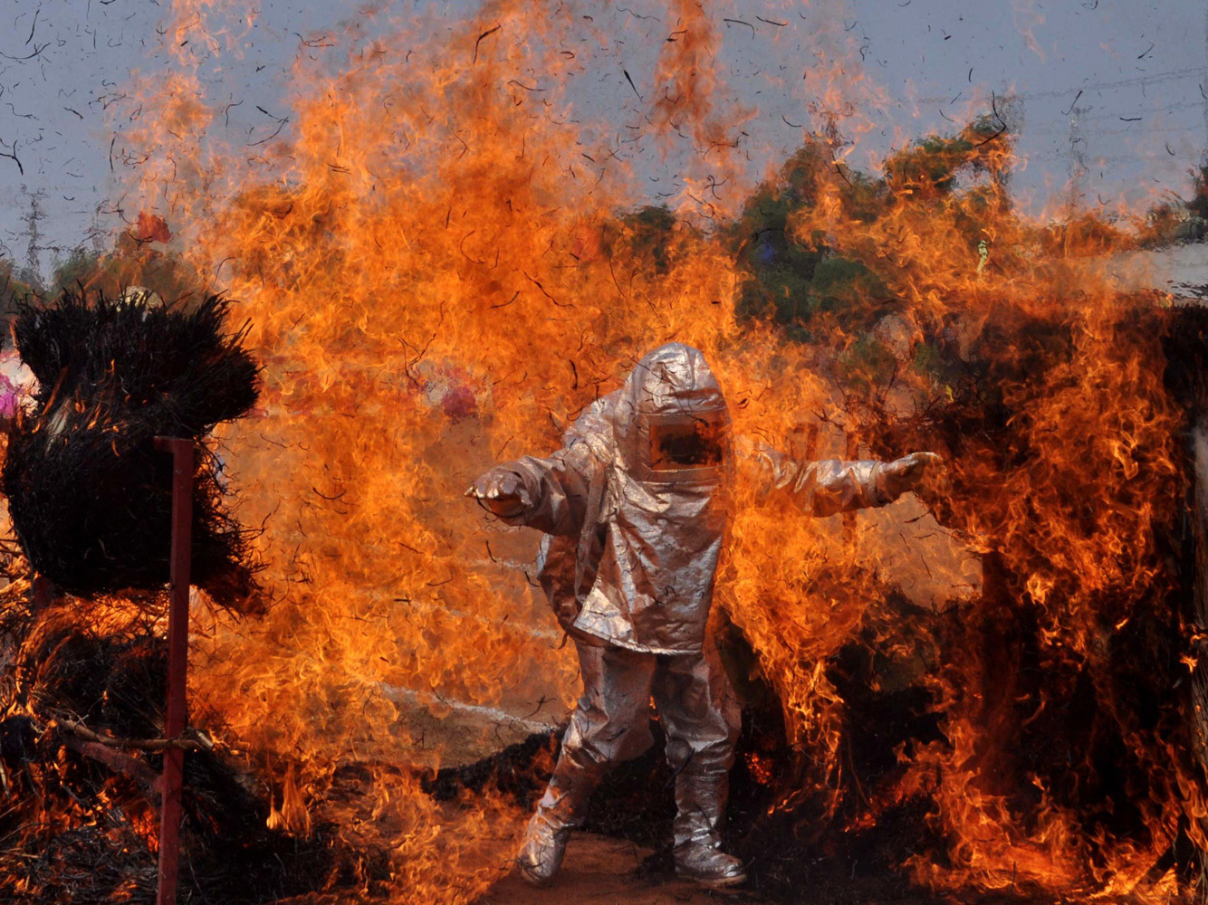 An Indian firefighter wearing a fire proximity suit walks through a wall of flames during a demonstration of their skills for Fire Safety Week in Bhubaneswar on April 15, 2014.
