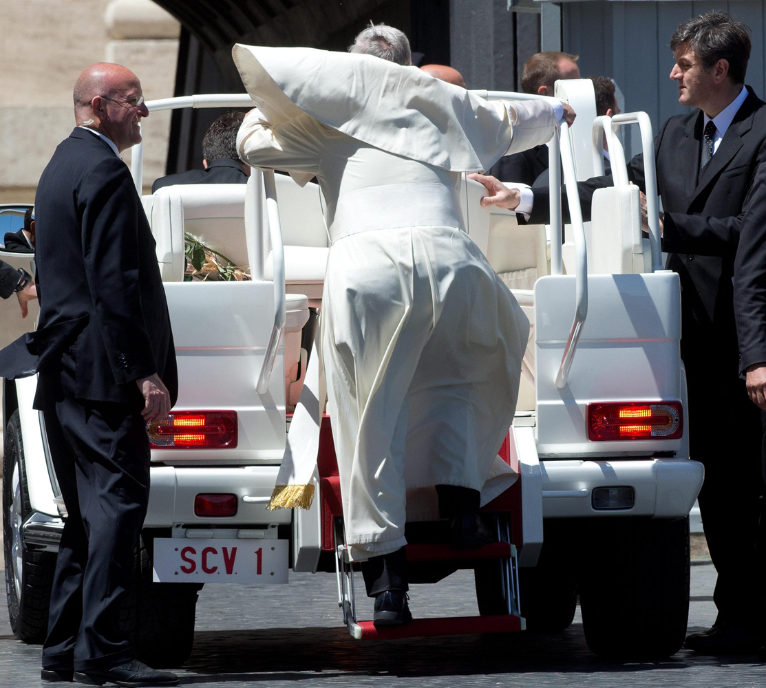 Pope Francis' cape flies up as he climbs the Popemobile at the end of his weekly Wednesday General Audience at St. Peter's Square in the Vatican City, May 14, 2014.