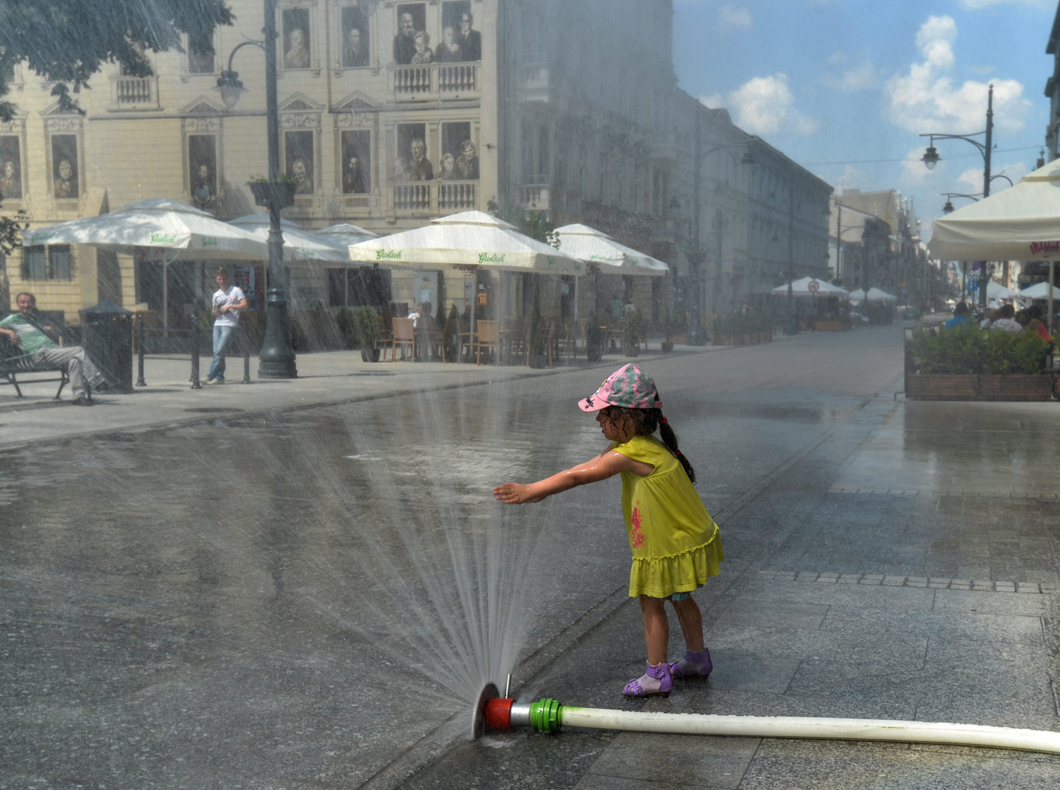 A girl plays with the water curtains that have been installed by firemen to bring relief to local people suffering from scorching heat on Piotrowska Street in Lodz, Poland on May 24, 2014.