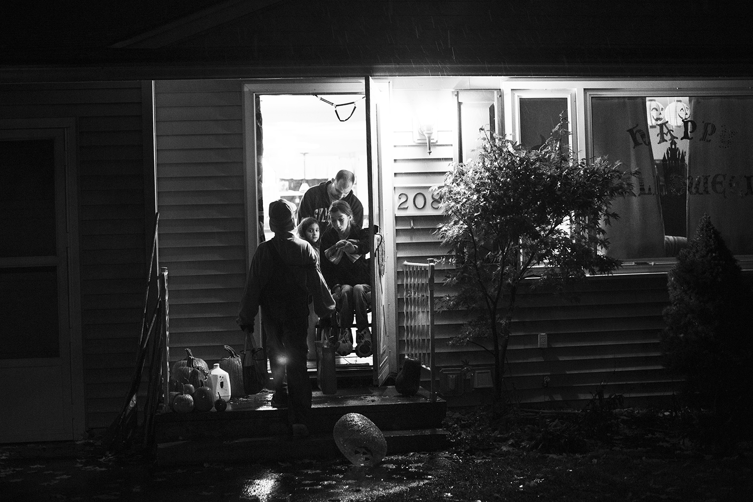 Gena hands out candy to trick-or-treaters on a rainy Halloween night while her siblings collect candy around the neighborhood.