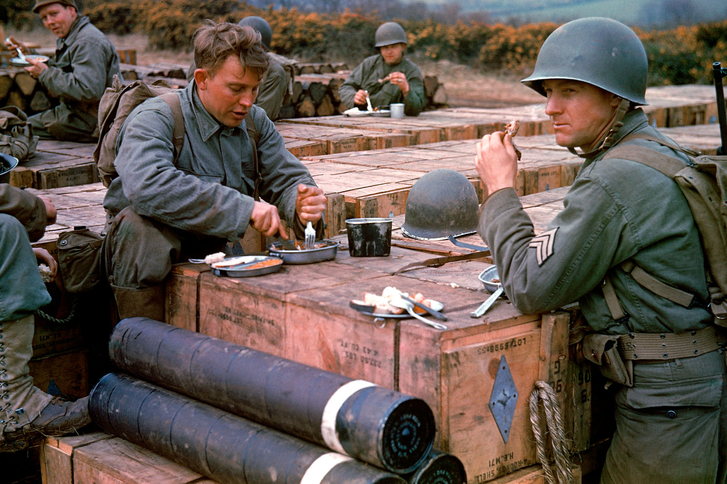 American combat engineers eat a meal atop boxes of ammunition stockpiled for the impending D-Day invasion, May 1944.