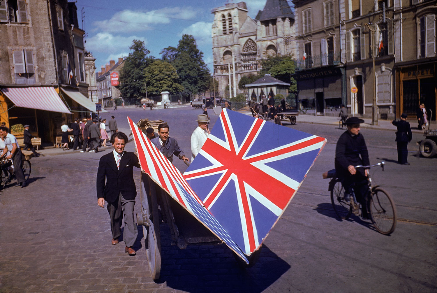 Frenchmen transport painted British and American flags for use in a parade, summer 1944.
