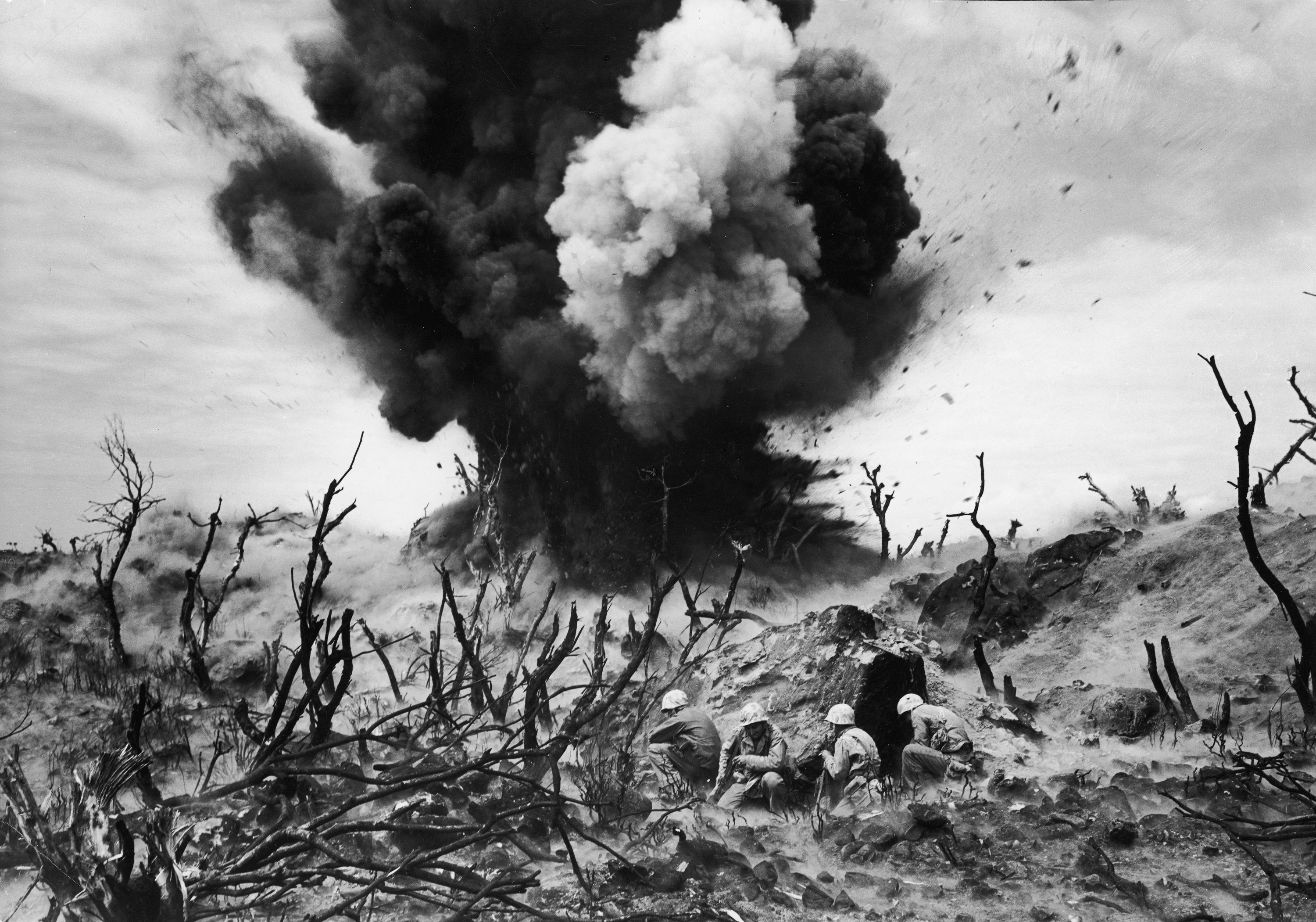 United States Marines (foreground) blow up a cave connected to a Japanese blockhouse on Iwo Jima, March 1945.