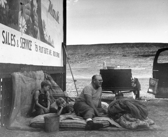 Family sleeping outside by a billboard alongside Route 30, Wyoming, 1948.
