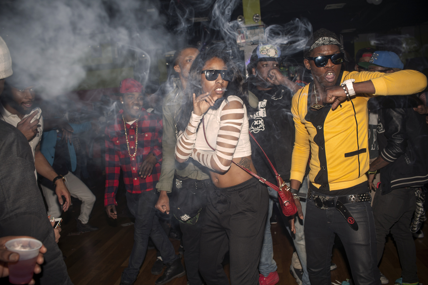 March 22nd, 2013. East Flatbush, Brooklyn. The Flavor Essence dance team moves through its choreography in unison as smoke clouds the air in a nightclub around 3am on a Thursday night. Videographers often attend the parties to make video of the dancers, which will be published on the internet on various websites that cater to the subculture. Teams often compete fiercely for the videographer's spotlight. (Natalie Keyssar)