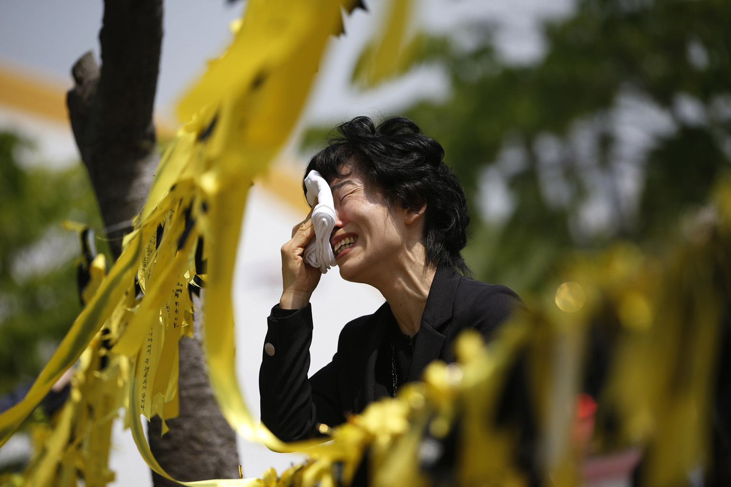 A mourner cries next to yellow ribbons dedicated to missing and dead passengers of sunken passenger ship Sewol, after paying tribute at the official memorial altar in Ansan