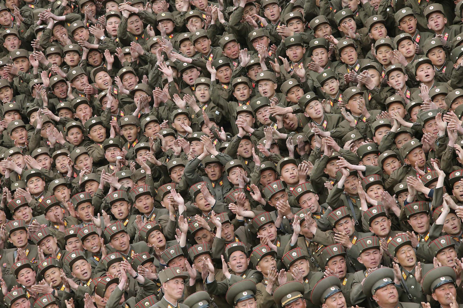 Soldier-builders of KPA Units 966, 462, 101, 489, who took part in building the workers' hostel of Kim Jong Suk Pyongyang Textile Mill, applaud during a photo session with North Korean leader Kim Jong Un