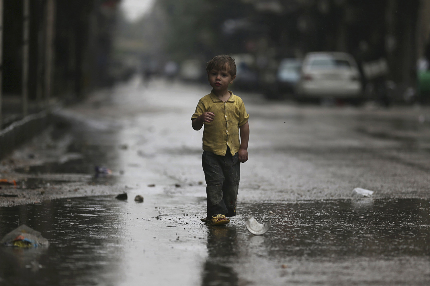 A child walks along a street during rainy weather in the Duma neighbourhood of Damascus