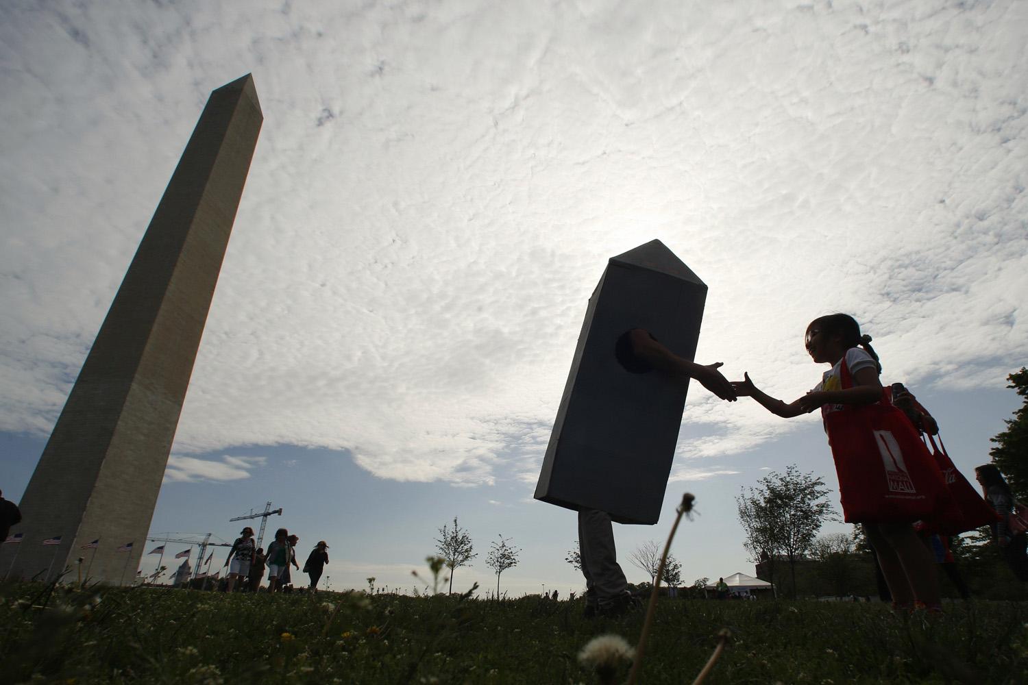 A girl shakes hands with a man dressed as the Washington Monument at the monument's re-opening ceremony in Washington, D.C., on May 12, 2014.