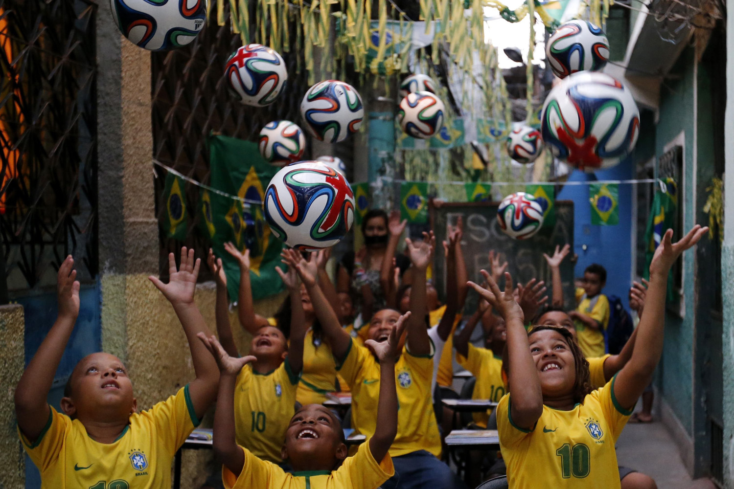 Children throw official 2014 FIFA World Cup soccer balls into the air during a protest against the 2014 World Cup, organized by the NGO Rio de Paz at the Jacarezinho slum in Rio de Janeiro on May 14, 2014.