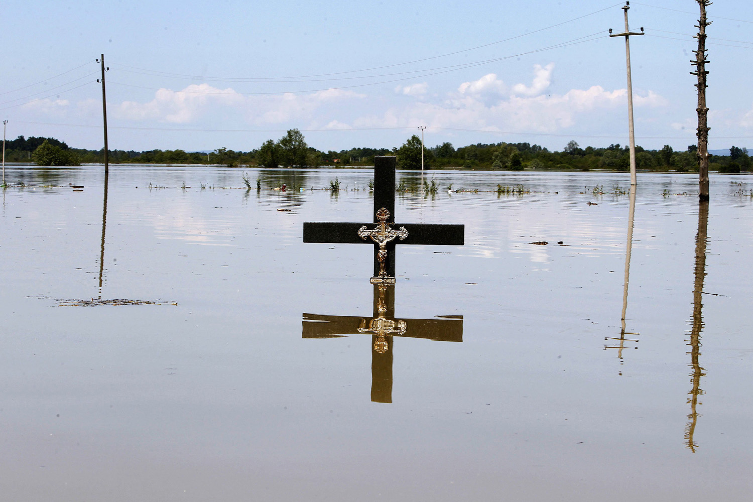 A cross is seen in floodwaters at a cemetery during heavy floods in the village of Vojskova