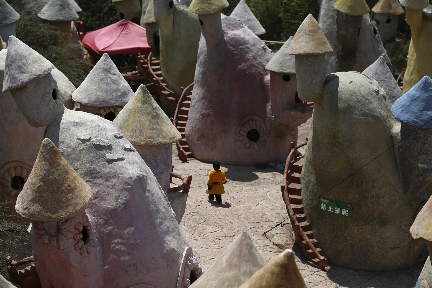 A dwarf walks in between mushroom-shaped houses after performances at Kunming World Butterflies Garden, Yunnan province on May 21, 2014.