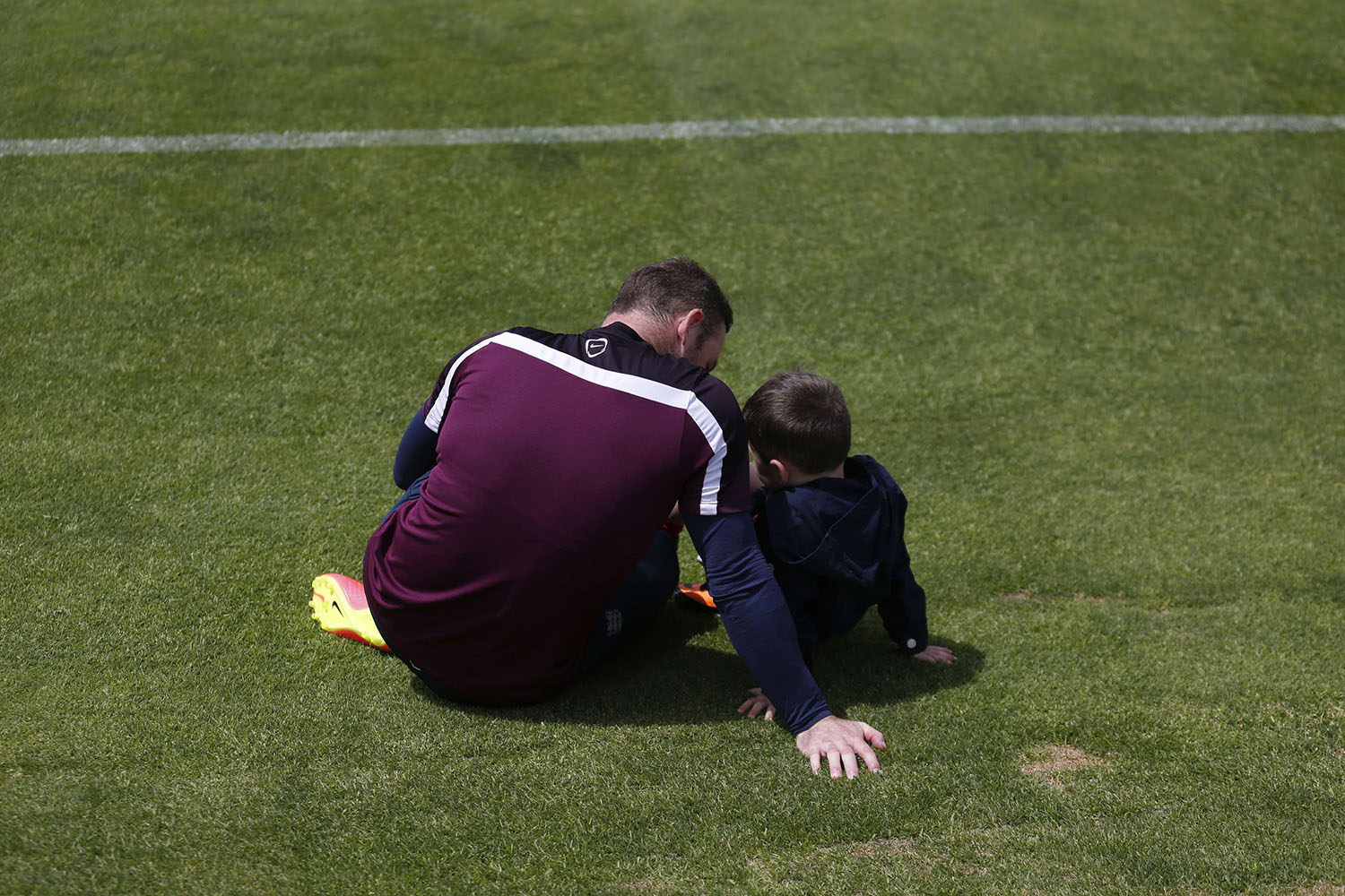 England's national soccer team player Wayne Rooney speaks with his son, Kai, after a training session in Almancil, near Faro in Portugal, on May 21, 2014.