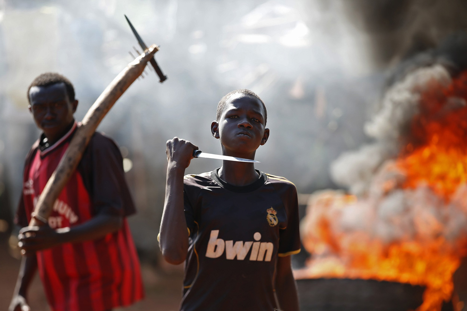 A boy gestures in front of a barricade on fire during a protest after French troops opened fire at protesters blocking a road in Bambari
