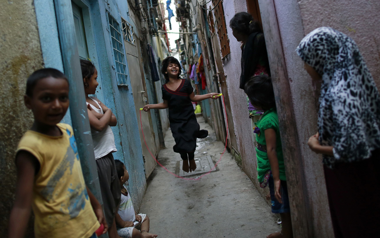 A girl jumps rope in an alley as others watch in Dharavi, one of Asia's largest slums in Mumbai on May 28, 2014.