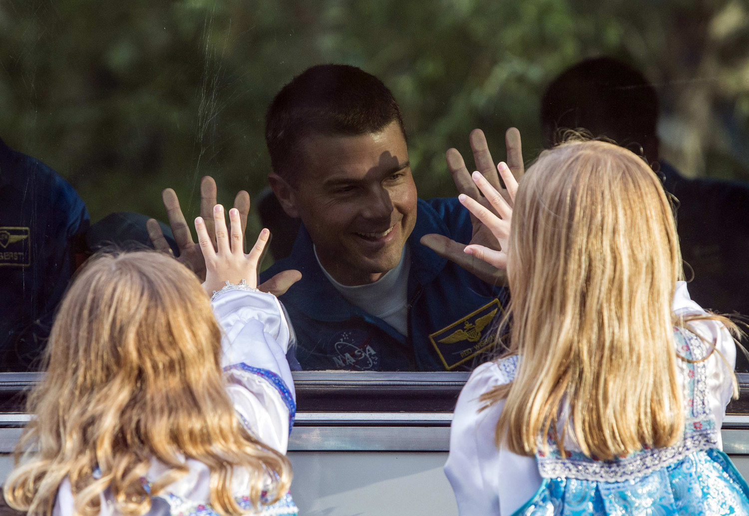 Reid Wiseman of the U.S., a member of the International Space Station crew, waves to his daughters from a bus before departure for a final pre-launch preparation at the Baikonur cosmodrome on May 28, 2014.