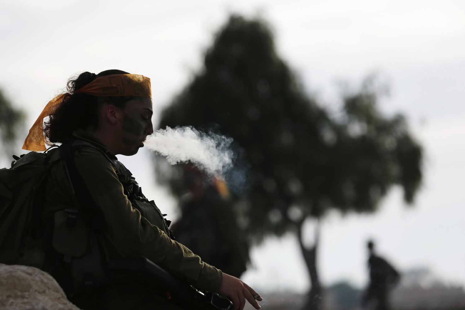 An Israeli soldier of Caracal battalion smokes after finishing a march in Israel's Negev desert