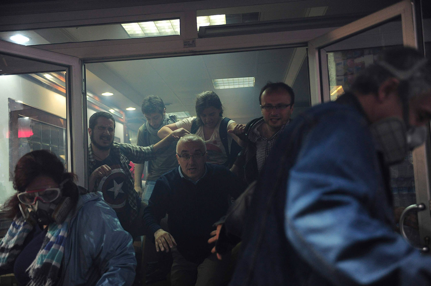 People try to escape from a cafe, after tear gas fired by riot police outside to disperse protesters seeped in, at central Istanbul, May 31, 2014.