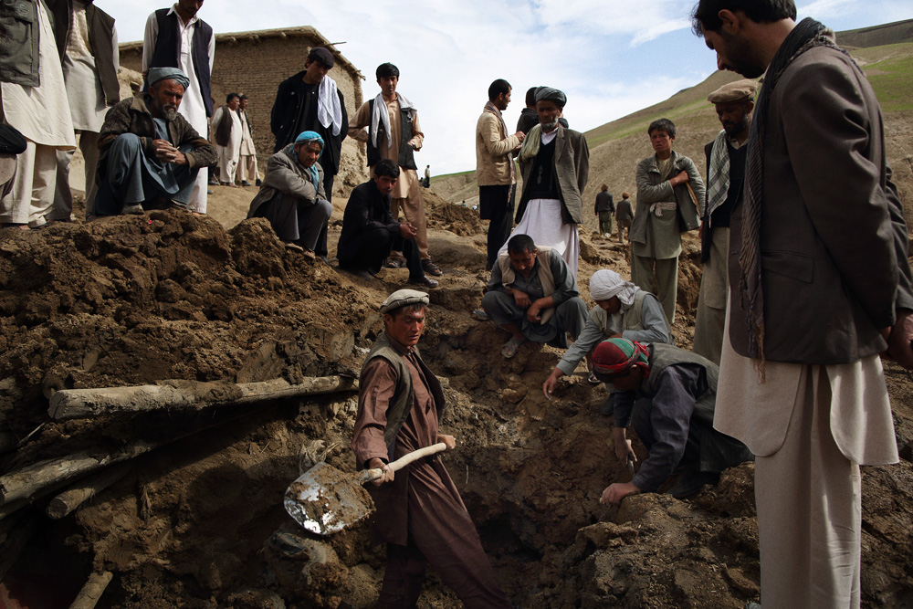 Approximately 24 hours after 2 landslides buried over 2000 residents of Argo district in the mountainous northeastern state of Badakhshan under hundreds of feet of mud. The first landslide buried some 300 homes and those who had been inside or on the streets at the time as well as those attending a wedding party. The second landslide struck as villagers attempted to rescue those trapped - digging with shovels and their bare hands. Today - Saturday - rescuers called off a search for survivors due to a lack of heavy machinery required for the massive task, however, some men continued to dig about above where there homes had once been. Mohammad Karim Khalili, one of Afghanistan’s two Vice Presidents along with a handful of ministers travelled from Kabul to pay their respects at the site of the landslide today. Saturday 3 May, 2014. Photo by Andrew Quilty / Oculi for TIME.