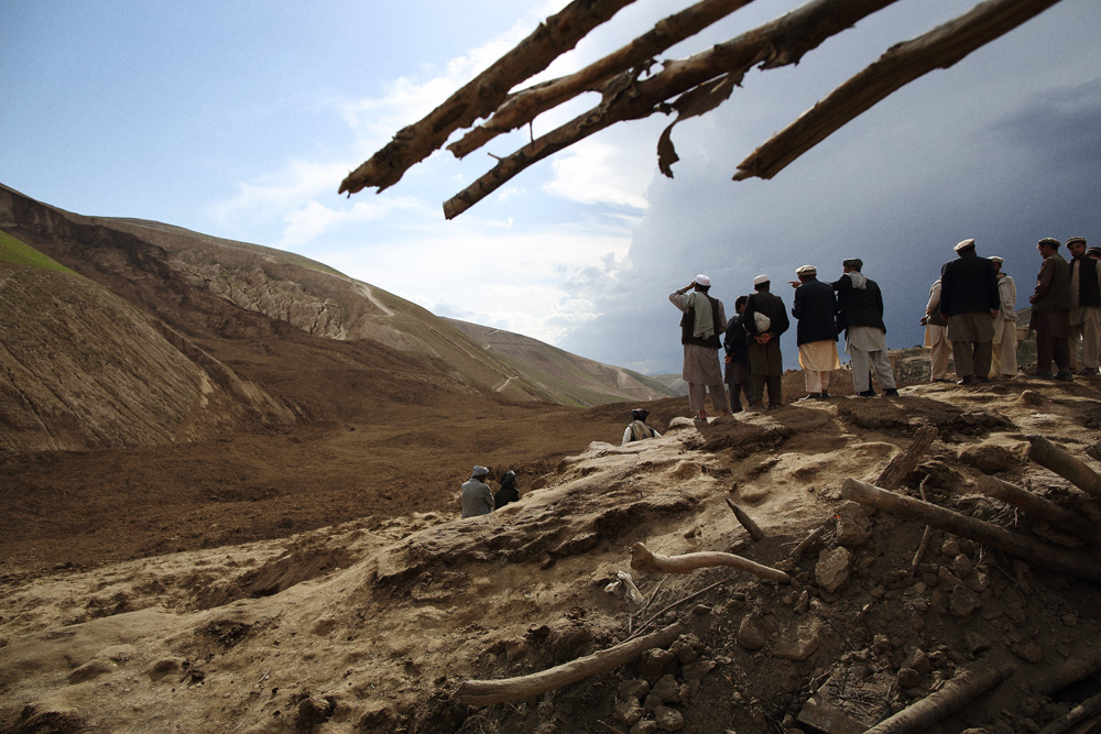 Approximately 24 hours after 2 landslides buried over 2000 residents of Argo district in the mountainous northeastern state of Badakhshan under hundreds of feet of mud. The first landslide buried some 300 homes and those who had been inside or on the streets at the time as well as those attending a wedding party. The second landslide struck as villagers attempted to rescue those trapped - digging with shovels and their bare hands. Today - Saturday - rescuers called off a search for survivors due to a lack of heavy machinery required for the massive task. Mohammad Karim Khalili, one of Afghanistan’s two Vice Presidents along with a handful of ministers travelled from Kabul to pay their respects at the site of the landslide today. Saturday 3 May, 2014. Photo by Andrew Quilty / Oculi for TIME. Men from the village look over the site of the landslide from a mound of mud that made it's way up the adjacent side of the valley. Saturday 3 May, 2014. Photo by Andrew Quilty / Oculi for TIME.