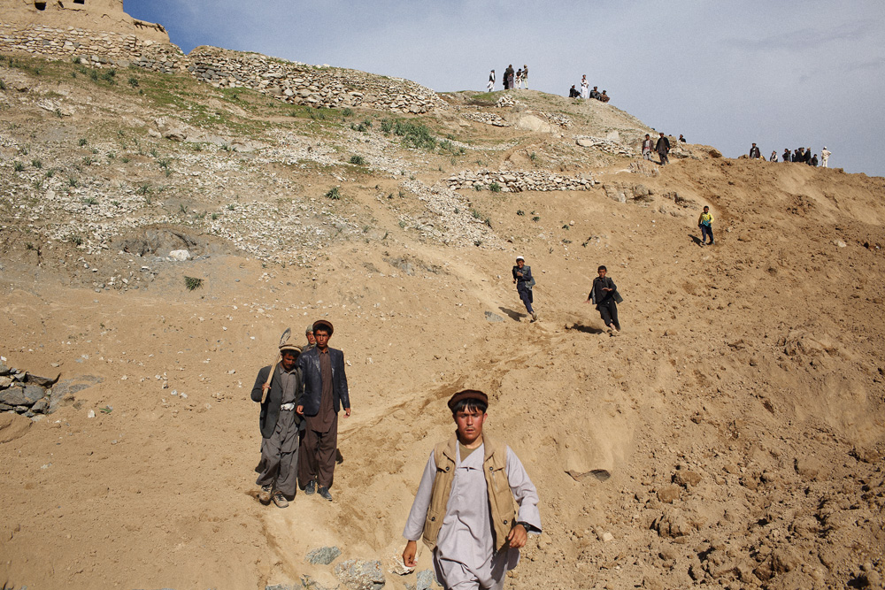 Approximately 24 hours after 2 landslides buried over 2000 residents of Argo district in the mountainous northeastern state of Badakhshan under hundreds of feet of mud. The first landslide buried some 300 homes and those who had been inside or on the streets at the time as well as those attending a wedding party. The second landslide struck as villagers attempted to rescue those trapped - digging with shovels and their bare hands. Today - Saturday - rescuers called off a search for survivors due to a lack of heavy machinery required for the massive task. Mohammad Karim Khalili, one of Afghanistan’s two Vice Presidents along with a handful of ministers travelled from Kabul to pay their respects at the site of the landslide today. Saturday 3 May, 2014. Photo by Andrew Quilty / Oculi for TIME. Men and boys - some carrying shovels - walk over mountains of dirt after visiting Argo district on foot from a nearby village to see if they could help in the rescue effort. Saturday 3 May, 2014. Photo by Andrew Quilty / Oculi for TIME.