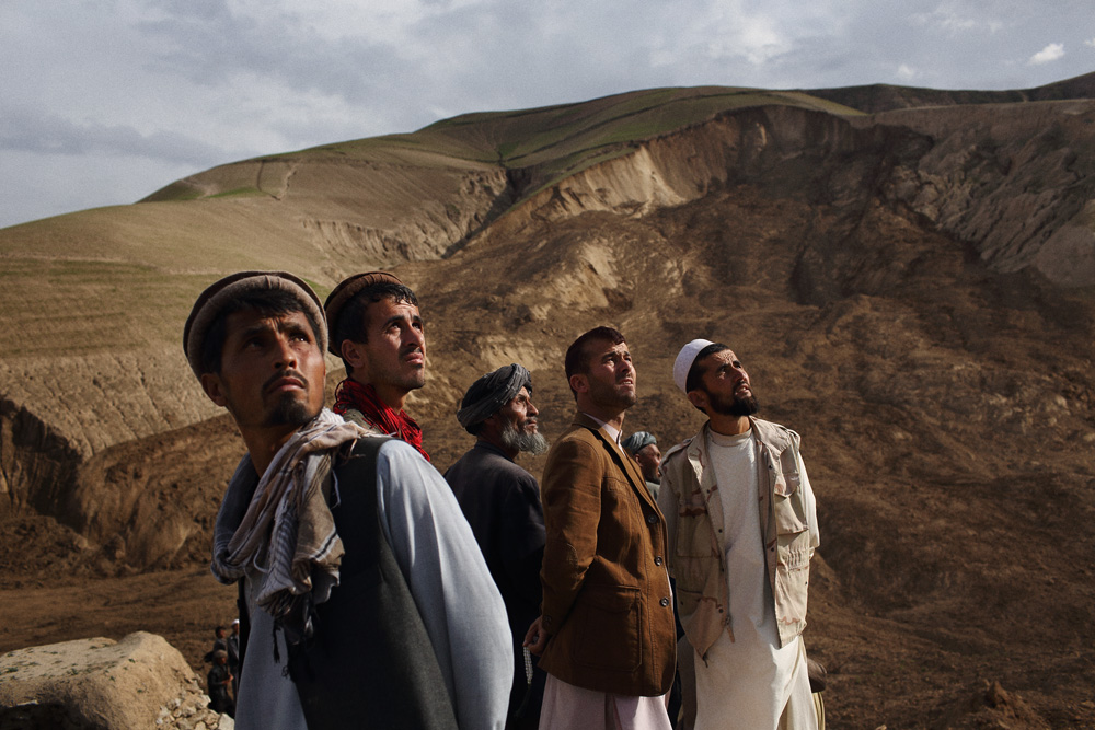 Approximately 24 hours after 2 landslides buried over 2000 residents of Argo district in the mountainous northeastern state of Badakhshan under hundreds of feet of mud. The first landslide buried some 300 homes and those who had been inside or on the streets at the time as well as those attending a wedding party. The second landslide struck as villagers attempted to rescue those trapped - digging with shovels and their bare hands. Today - Saturday - rescuers called off a search for survivors due to a lack of heavy machinery required for the massive task. Mohammad Karim Khalili, one of Afghanistan’s two Vice Presidents along with a handful of ministers travelled from Kabul to pay their respects at the site of the landslide today. Saturday 3 May, 2014. Photo by Andrew Quilty / Oculi for TIME. With the landslide in the background, men look to the sky as an Afghan National Army helicopter carrying Mohammad Karim Khalili, one of Afghanistan’s two Vice Presidents flies over the disaster. Saturday 3 May, 2014. Photo by Andrew Quilty / Oculi for TIME.