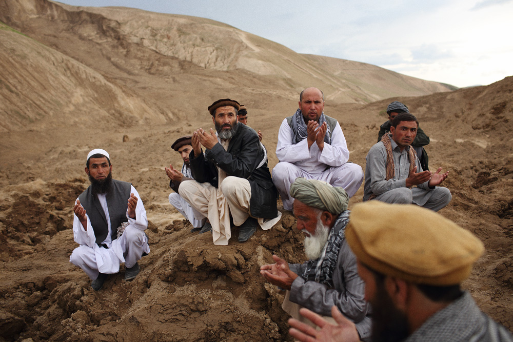 Approximately 24 hours after 2 landslides buried over 2000 residents of Argo district in the mountainous northeastern state of Badakhshan under hundreds of feet of mud. The first landslide buried some 300 homes and those who had been inside or on the streets at the time as well as those attending a wedding party. The second landslide struck as villagers attempted to rescue those trapped - digging with shovels and their bare hands. Today - Saturday - rescuers called off a search for survivors due to a lack of heavy machinery required for the massive task. Mohammad Karim Khalili, one of Afghanistan’s two Vice Presidents along with a handful of ministers travelled from Kabul to pay their respects at the site of the landslide today. Saturday 3 May, 2014. Photo by Andrew Quilty / Oculi for TIME. Men gathered to offer prayers on the mountains of mud that buried many of their firends and relatives. Saturday 3 May, 2014. Photo by Andrew Quilty / Oculi for TIME.