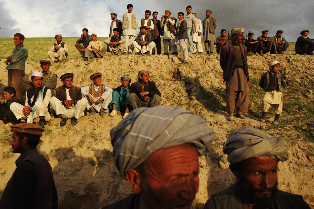 2 days after 2 landslides buried Boys and men watch as aid is distributed, May 5, 2014. estimated 2000 residents of Abi Barak in the Argo district of the mountainous northeastern state of Badakhshan under hundreds of feet of mud. The first landslide buried some 300 homes and those who had been inside or on the streets at the time as well as those attending a wedding party. The second landslide struck as villagers attempted to rescue those trapped - digging with shovels and their bare hands. Boys and men watch on as aid is distributed to masses of men. Monday 5 May, 2014. Photo by Andrew Quilty / Oculi for TIME.
