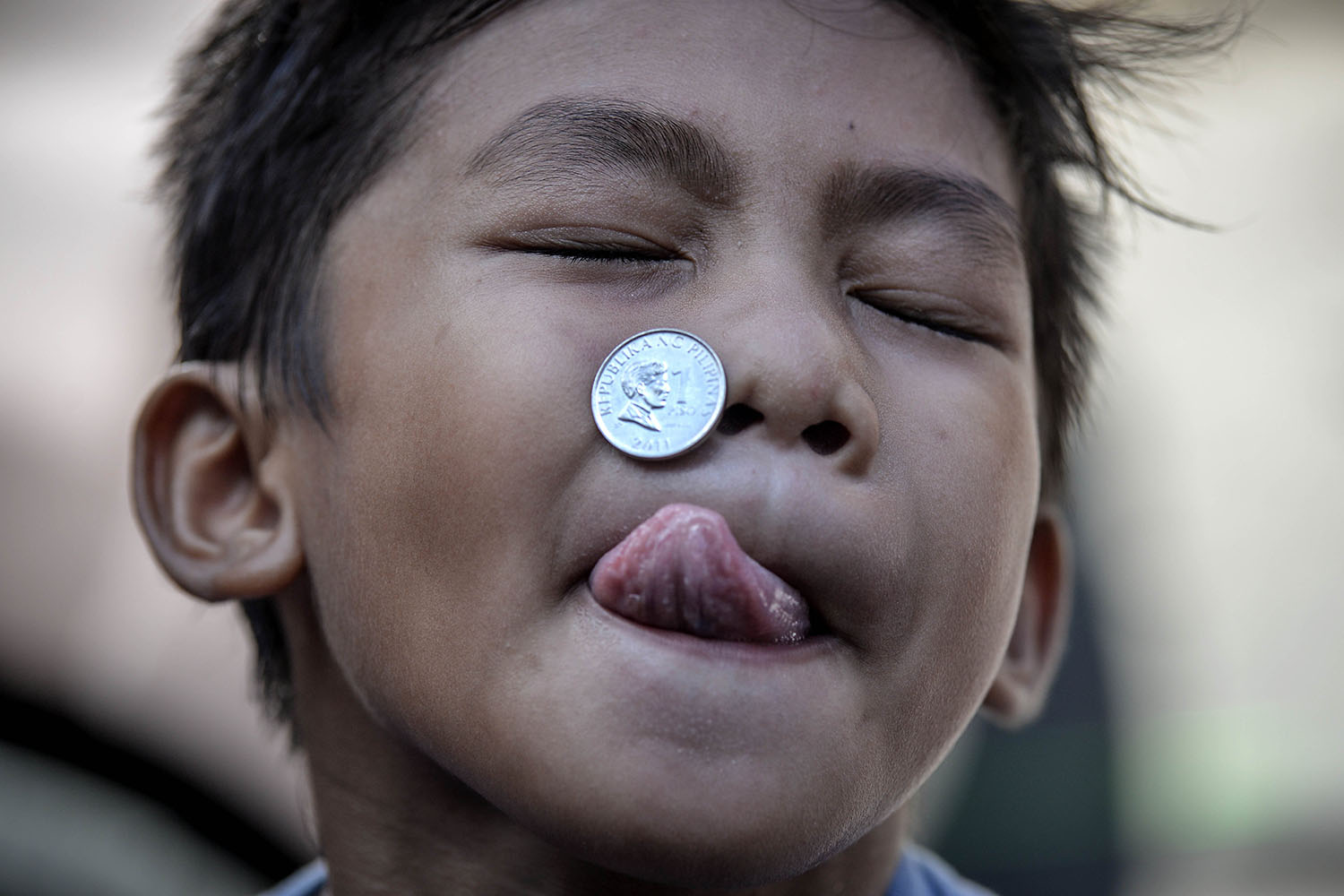 A boy contorts his face as he competes in a parlor game trying to move a coin from his forehead to his mouth as part of the feast day of Saint Rita of Cascia in Paranaque, Philippines, on May 18, 2014.