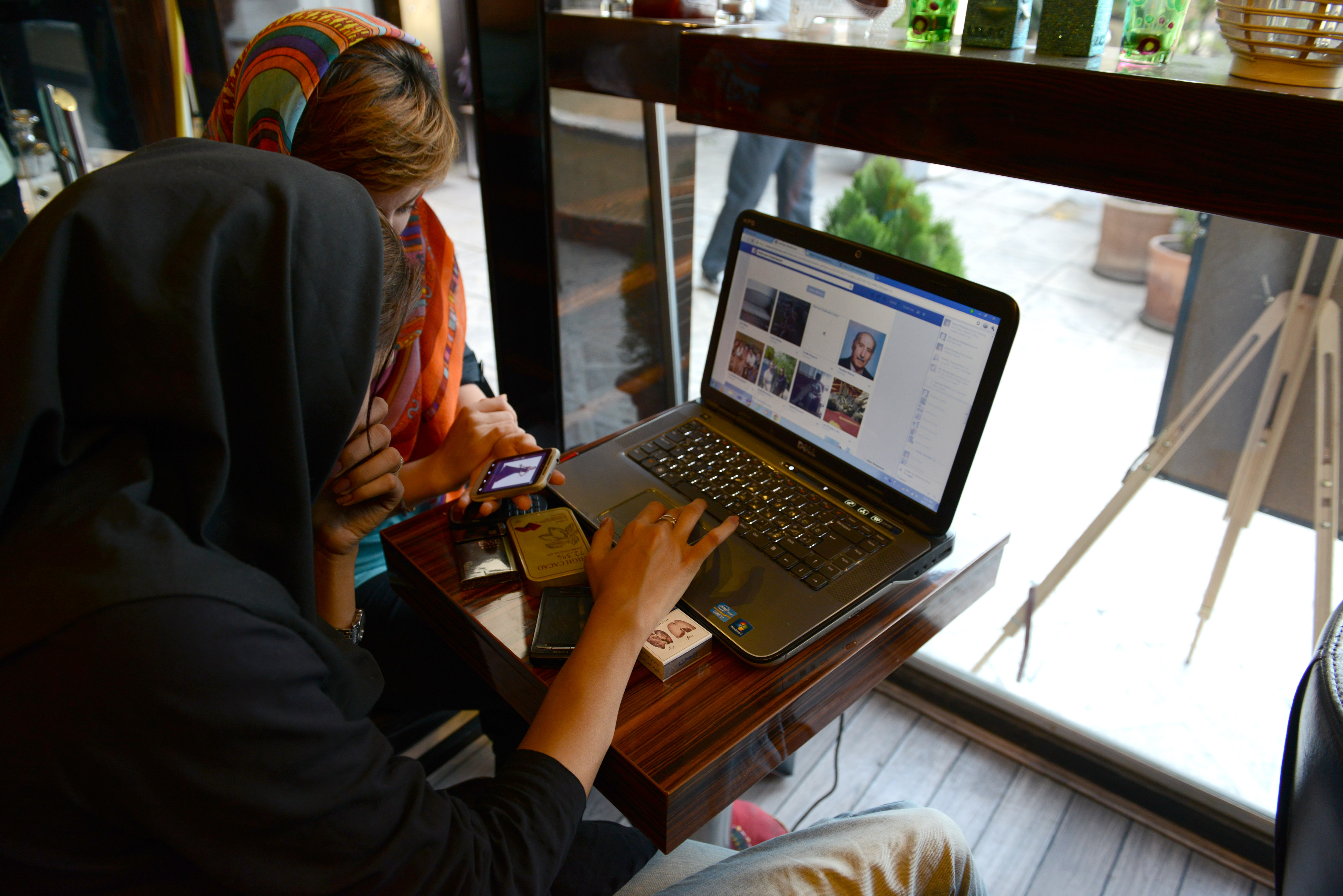Two girls sit in a north Tehran coffee shop using Facebook and looking on the mobile phone at online fashion clothing in Tehran, Iran on October 13, 2013. (Kaveh Kazemi—Getty Images)