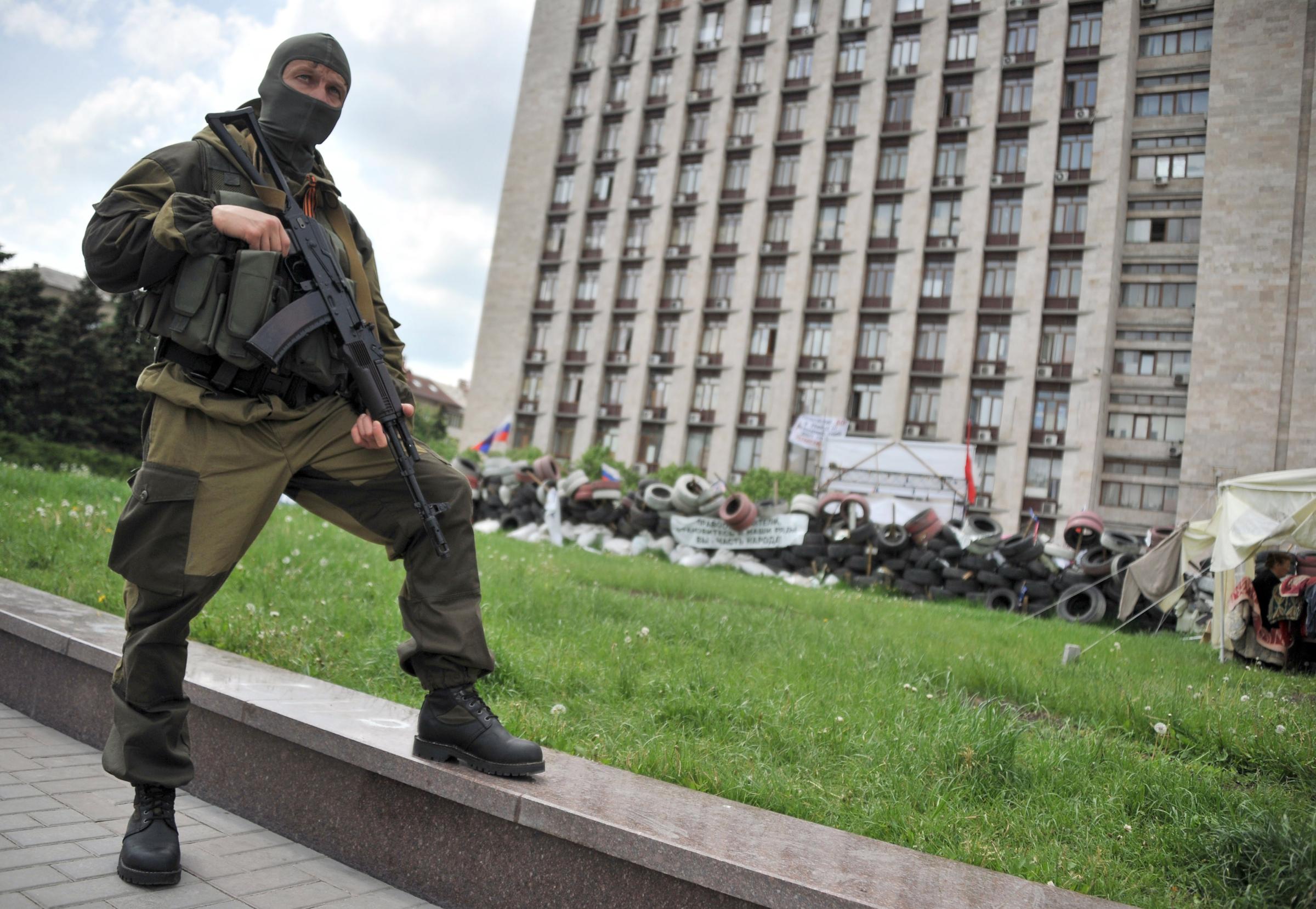 An armed pro-Russia militant stands guard as the self-styled governor of the so-called "People's Republic of Donetsk" speaks to the media near the regional state building seized by separatists in the centre of the eastern Ukrainian city of Donetsk on May 13, 2014.