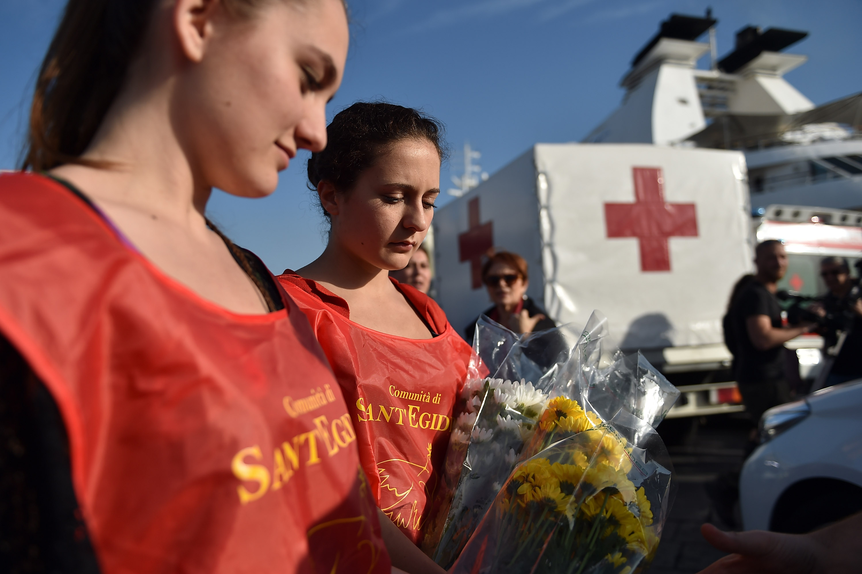 Sant'Egidio Community volunteers hold flowers while waiting arrival of Italian Navy Ship Grecale arriving at the Port of Catania, carrying 206 migrants and 17 bodies of the victims of a shipwrecked boat between Sicily and the north of Africa on May 13, 2014 (Tullio M. Puglia—Getty Images)