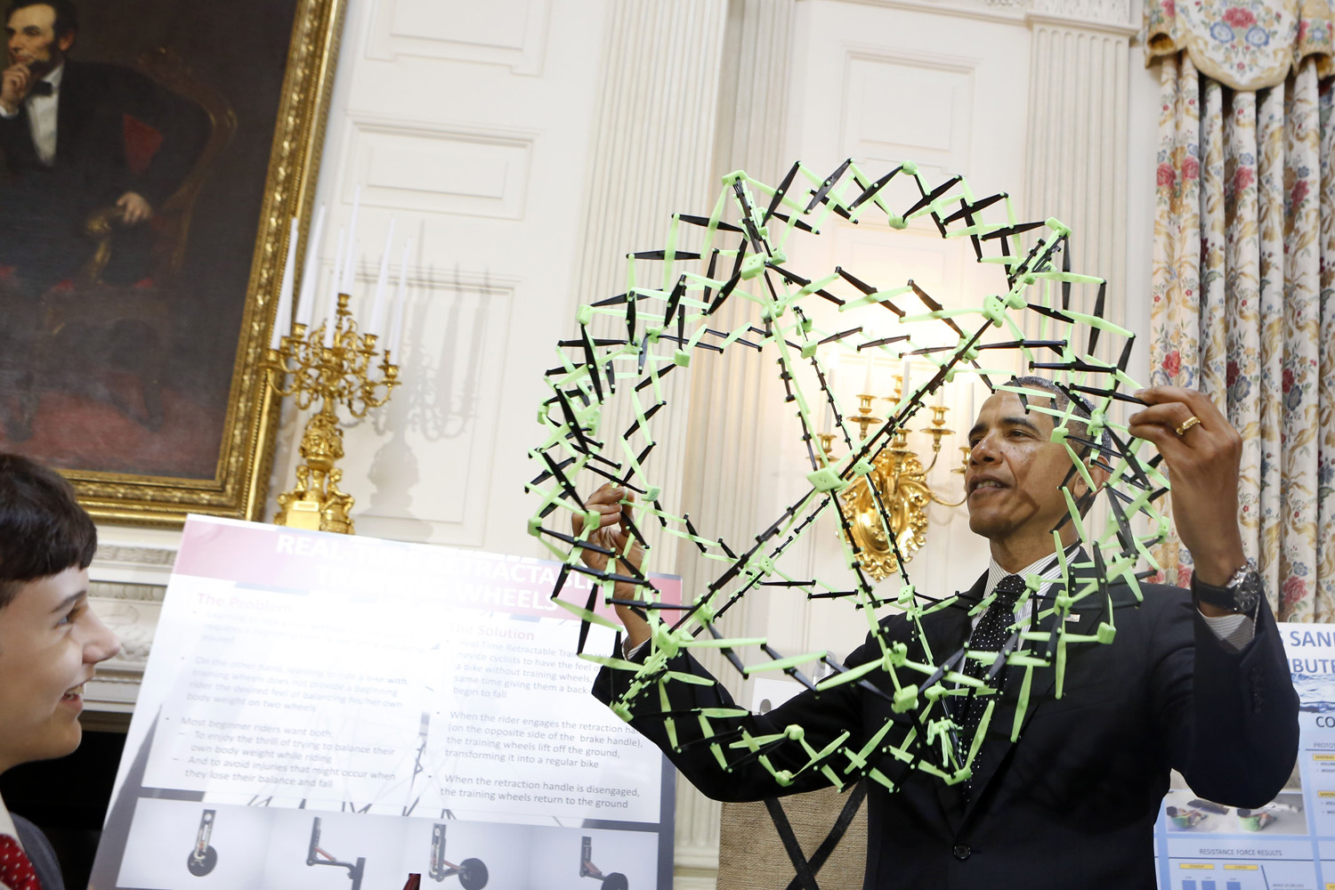 U.S. President Barack Obama looks at the project of Peyton Roberston (left) from Ft. Lauderdale, Fla., winner of the Discovery 3M Young Scientist, for his "Sandless sand bags" project at the 2014 White House Science Fair in Washington, D.C., May 27, 2014.