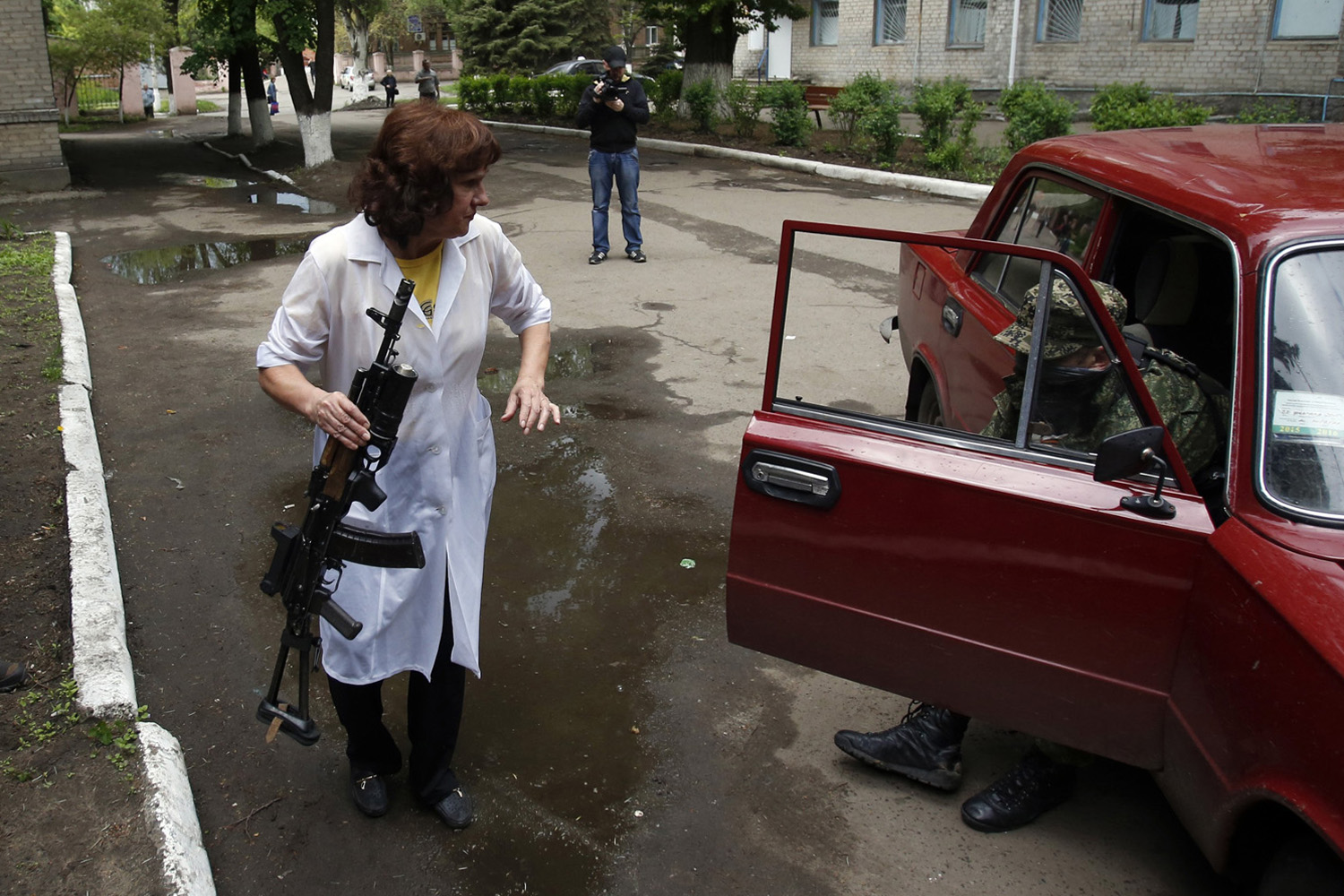 A nurse holds a gun as she helps a wounded Pro-Russian gunmen to get out of the car in front of local hospital in Slovyansk, eastern Ukraine, on May 5, 2014.