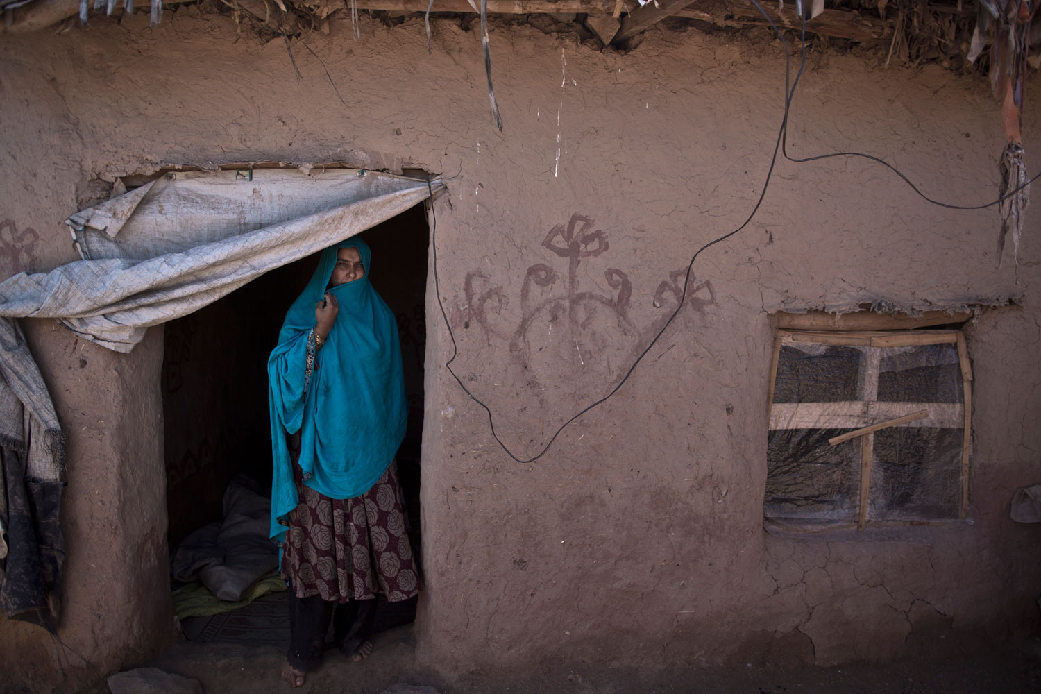 Afghan refugee Belquis Elias, 42, a mother of 4 children who are now adults, at the doorway of her mud house on the outskirts of Islamabad on March 30, 2014. Elias and her husband fled their hometown of Khairabad 19 years ago and took refuge in Pakistan.
                              
                               My two sons are living in Afghanistan with their own families, but they are still my children and I am always worried about them.