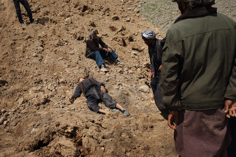 A young boy whose father was killed in the landslide faints as others dig above where his house lies buried, May 5, 2014.